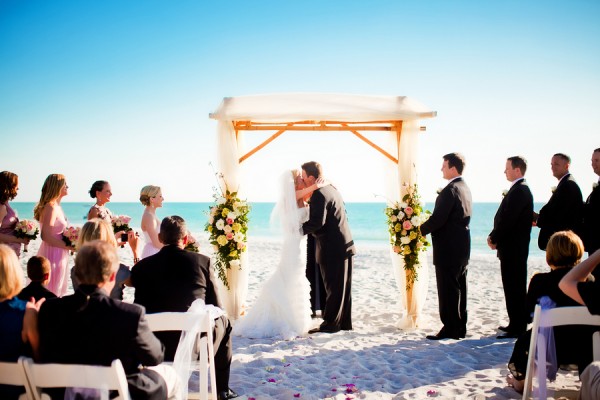 red and white rose wedding arches on the beach